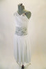 White dress has lace centre waist panel that is open at the back. Top has a sheer fabric cascading from right shoulder across the bust area around to the left waist. There is a crystal brooch accent at the left shoulder and silver applique at the back. Comes with crystal hair barrette. Side
