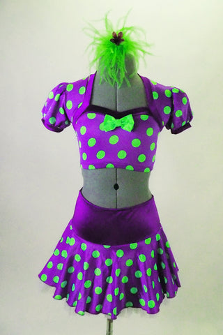 2-piece costume is purple with neon green polka dots has faux pouf sleeved shrug top with green bow. The matching skirt has wide purple waistband with back bow details. Comes with green feather hair accessory. Front