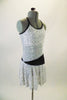 White knee-length dress has silver swirl pattern and black piping with back cross straps. The black waistband starts at the right hip and widens as it wraps around the back and front joining at the left side. Comes with a hair accessory. Right side