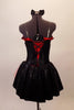 Black and red costume has a black bodice decorated with crystals with red ruffle along bustline that looks strapless but has clear shoulder straps. The lower back has laced corset accent over a red insert. The bottom is red shorts with black edged ruffles below an open front bustle skirt with red tulle and black overlay. Comes with matching crystaled gauntlets hair accessory. Back