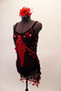 Red and black glitter dress has a red center panel with bust area draped with large red metallic polka dot sequins on black sheer. The matching sarong skirt also has dangling sequin trim. The costume has black velvet trim and bottom. Comes with a hair accessory. Side
