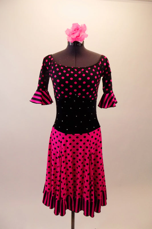 Pink and black, off the shoulder, knee-length dress has an alternate colour block of hot pink and black polka dots and stripes with black velvet crystal scattered midriff. The nude straps hold the dress in place. Comes with a hair accessory. Front