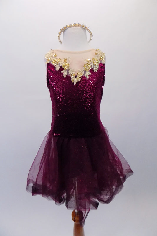 Pretty burgundy sequined dress has nude mesh upper and is accented with wide gold floral applique. The attached mesh high-low skirt has wide stiffened mesh banding to create fullness and ruffles. Comes with rhinestone hair-band accessory. Front