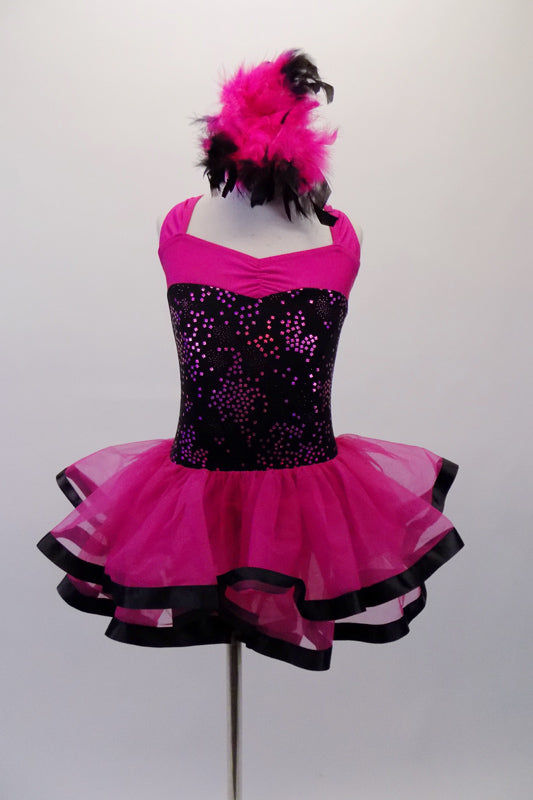 Fuchsia dress has black sparkle torso and wide cross-back straps. The fuchsia sheer double layered attached skirt has black ribbon edging. Comes with pink and black feather hair accessory and sparkle gauntlets. Front