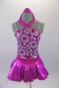Sweet two-piece costume has white circular sparkle pattern on the bodice of a metallic pink base. The hater neck straps originate from a ring at the front of the bodice. The accompanying pull-on skirt is metallic pink with white tulle for volume. Comes with a purple floral hair accessory. Front