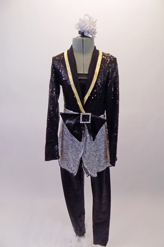 Classy three-piece costume includes a pair of black shiny leggings and matching black bandeau top. The jacket is a black and silver sequined long blazer style with gold accented lapels, cross front and a large front bow accent. Comes with matching silver hair accessory. Front