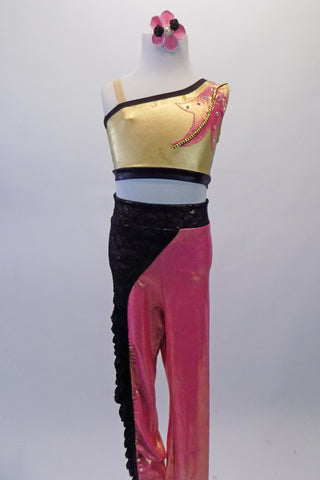 Sassy two-piece costume had a one-shoulder gold half top with salmon coloured leaf motif, black banding and crystal accents. The matching salmon leggings have a black swirled lace overlay extending from the waistband along the right hip and down the right leg. Comes with a hair accessory. Front