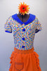 50s housewife themed, pouffe sleeved dress is a white base with colourful squares of blues, yellow & orange. The blue theme is repeated in the collar, sleeve cuffs, buttons & ruffled skirt hem. The orange attached apron compliments the square pattern in the dress with blue crystal accents. Comes with a hair accessory. Front zoomed