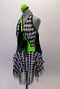 Black & white checkered harlequin themed dress has a lime green cross-over, halter bodice with attached black mesh kerchief accents cascading throughout. Swarovski crystals are scattered within the checkered pattern of the fabric that sits over layers of black tulle. Comes with a green floral hair accessory. Side