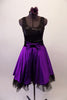 Purple and black tank style dress has a black scoop-neck bodice and black velvet waistband with crystal accents and purple front bow. The attached purple calf length skirt has layers of black tulle for a full petticoat. Comes with floral hair accessory and lace edged purple gauntlets. Front