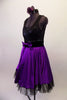 Purple and black tank style dress has a black scoop-neck bodice and black velvet waistband with crystal accents and purple front bow. The attached purple calf length skirt has layers of black tulle for a full petticoat. Comes with floral hair accessory and lace edged purple gauntlets. Side