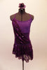 Plum cross-back short unitard base dress has purple mesh midriff & crystal accents along neckline. A purple sequin overlay is attached at right bust & cascades across front & back revealing leotard beneath. The sequin overlay acts as the skirt with a distinct plum waistband. Comes with floral hair accessory. Front