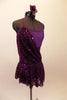 Plum cross-back short unitard base dress has purple mesh midriff & crystal accents along neckline. A purple sequin overlay is attached at right bust & cascades across front & back revealing leotard beneath. The sequin overlay acts as the skirt with a distinct plum waistband. Comes with floral hair accessory. Right side