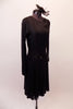 Simply elegant black long-sleeved dress has sheer floral lace left sleeve, shoulder and waistband with a lace cascade from right hip. Comes with flack rose fascinator hair accessory. Right side