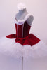 Gorgeous red velvet tutu has a red leotard base with white boning & princess cut. The neckline is draped with white chiffon that joins at the center of the back.  The skirt is comprised of a white tulle pull-on tutu with chiffon & red velvet overlay. Comes with white floral hair accessory & clear straps. Left side
