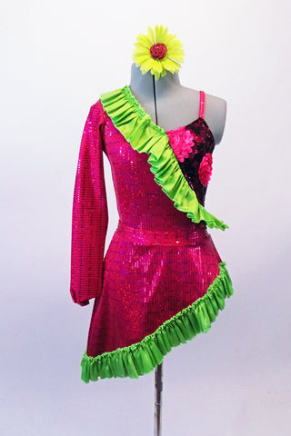 Two-piece costume has fuchsia rectangle sequined one sleeved shrug with a lime green ruffle that exposes a black lace covered fuchsia leotard with 3-D floral applique. The matching angled pull-on skirt is fuchsia sequined with green ruffle. Comes with a green floral hair accessory. Front