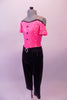 Fully sequined bright pink and black capri-length unitard is an off-shoulder top with black piping, cap sleeves, nude shoulder straps and black button accents. The attached black capri pat is a straight leg with gathered waistband and crystal ring buckle accent. Comes with a hair accessory. Side