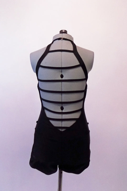 Unique black halter neck, short unitard has a simple front but an intricate back comprised of a series of straps in varying lengths to resemble a curved ladder. Back