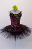 Pretty black pleated six-layer platter tutu has an attached bodice and overlay adorned with a glittery rose floral pattern in shades of pink, green and fuchsia. Comes with a green floral hair accessory. Front