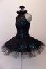 Stunning black sequined lace tutu has a ruffled halter collar neck with a shimmery teal underlay with sweetheart bust. The back has vertical angled straps for support. The bodice and overlay are attached to the six-layer black pleated tutu. Comes with a black floral hair accessory. Side