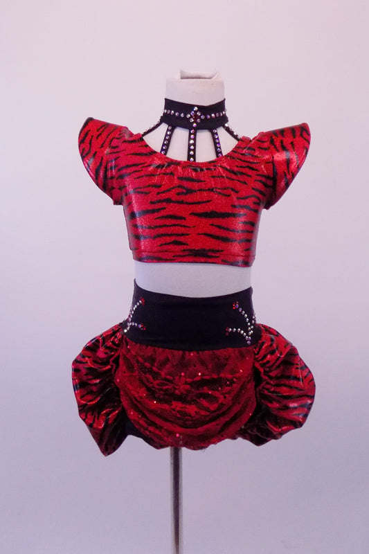 Two-piece black & red tiger stripe costume has a choker style collar attached by a series of straps covered in Swarovski crystals. The padded shoulders create a dramatic flair. The matching bottom is a high-waisted brief with crystal designs & pouffe bustle. Has red lace draping at the front. Comes with hair accessory. Front