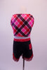 Two-piece cowboy themed costume has a pink, red and navy tartan half-top with red crystalled collar and tie front. The bottoms are a stretch denim short with red crystalled waistband and faux back pocket. The shorts are trimmed with red fringe for a western feel. Comes with sparkled mini cowboy hat and denim fringe. Back