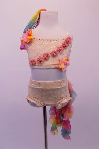 Nude lace 2-piece costume scattered with crystals & has crystal covered neckline & cross straps. A cascade of pink tiny rosettes on the bust. There are two large colourful chiffon rosettes at the front right shoulder & back of left hip. A long ruffled rainbow scarf cascades from the left hip. Comes with rainbow scarf. Front