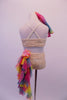 Nude lace 2-piece costume scattered with crystals & has crystal covered neckline & cross straps. A cascade of pink tiny rosettes on the bust. There are two large colourful chiffon rosettes at the front right shoulder & back of left hip. A long ruffled rainbow scarf cascades from the left hip. Comes with rainbow scarf. Back