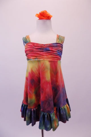 Deep jewel colours of blue red yellow & green combine in a 60s inspired hippie tie-dye style empire waist dress. The gathered bust gives rise to wide shoulder straps & a lower back. The knee length dress has a large ruffle at the bottom. Comes with an orange floral hair accessory. Front