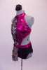Short unitard gives the appearance of a 2-piece. The metallic fuchsia pink halter top is covered along the right front and hip by a circular chain-like cascading sequin fabric. The top is attached to the shorts at two points in the front.  Open back has two vertical straps. Comes with a black floral hair accessory. Left side
