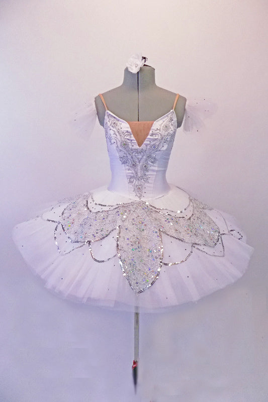 Snow white professional pleated & hand tacked 9-layer pancake tutu has attached bodice. The tutu has a triple scallop overlay with alternating white & silver sequined lace. The tutu is scattered with Swarovski crystals. The attached bodice is a deep front sweetheart cut with nude mesh centre inlay & lined with lace and crystals. Front