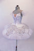 Snow white professional pleated & hand tacked 9-layer pancake tutu has attached bodice. The tutu has a triple scallop overlay with alternating white & silver sequined lace. The tutu is scattered with Swarovski crystals. The attached bodice is a deep front sweetheart cut with nude mesh centre inlay & lined with lace and crystals. Side