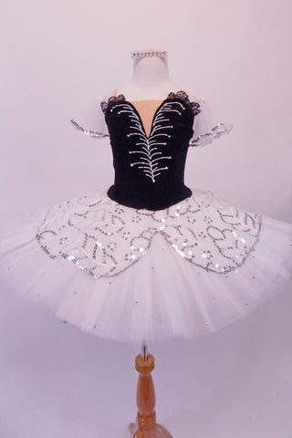 Pleated, hand tacked pancake tutu is a beautiful contrast of black & white. The tutu is scattered with crystals & has a silver sequined overlay. The black velvet bodice has a deep sweetheart cut with nude mesh centre & hand painted silver branch design. Comes with white tulle armbands and crystal hair barrette. Front