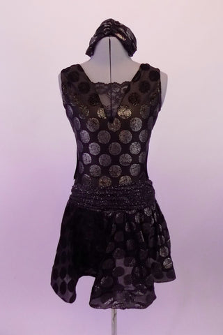 Black semi-sheer leotard dress has antique gold polka dots & is fully lined in the body. The bust is a low deep V with a black lace centre insert. The back is open with a single clip bra closure & the open sides curve into the front torso. The ruched glittery waistband compliments the attached polka dot skirt. Front