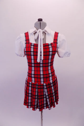 Red white and navy tartan school girl style costume has attached pleated skirt with a built-in brief. The separate white pouffe sleeved blouse has snap front closure and tie front attached to the collar. Front