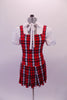 Red white and navy tartan school girl style costume has attached pleated skirt with a built-in brief. The separate white pouffe sleeved blouse has snap front closure and tie front attached to the collar. Front