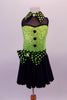Back and lime green sequined costume has faux sweetheart bust with a black mesh upper and a green and black polka dot collar that matches the waistband and large bow accent. The back is open with corset style straps that hold the torso together. The attached black skirt completes the look. Comes with polka dot gauntlet and hair accessory. Front