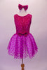 Magenta dress has sequined tank style bodice with scoop back. The skirt is sheer polka dot tulle and has a bow accent at the front centre of the waistband. Comes with matching sequined hair bow. Front