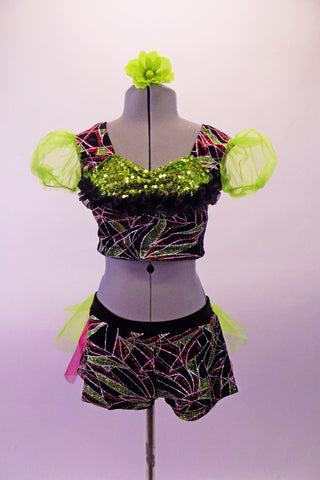 Two-piece costume dazzles with a silver-pink & green abstract leafy glitter design on black velvet. The top has line green organza pouffe sleeves & a green pure sequined pop-out bust edged in black lace ruffle. The matching shorts have a back bustle in lime green & hot pink organza. Comes with green hair flower. Front