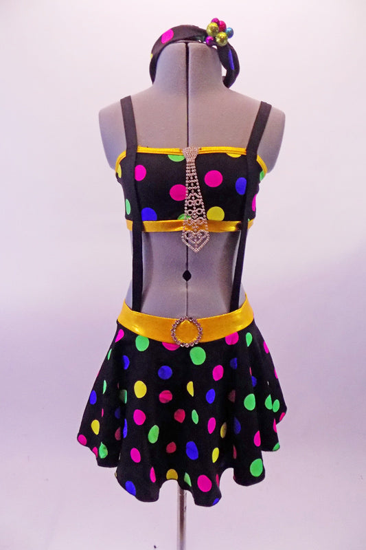 Black & colourful polka dot costume has a bandeau top and short circle skirt attached by elastic suspender bands to create a single piece. The waistband is yellow and there is a large tie-shaped crystal brooch accent attached to the front of the bandeau top. Comes with a matching bobbled headband. Front