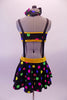 Black & colourful polka dot costume has a bandeau top and short circle skirt attached by elastic suspender bands to create a single piece. The waistband is yellow and there is a large tie-shaped crystal brooch accent attached to the front of the bandeau top. Comes with a matching bobbled headband. Back