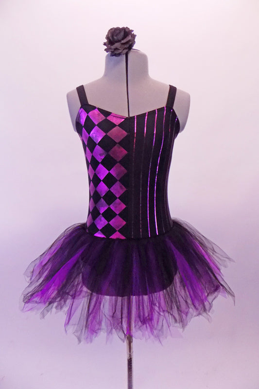 Black and purple-pink camisole leotard dress has a diamond pattern on the right side and pin-stripes on the left. The black and purple tulle attached skirt softens the abstract look. Comes with a black floral hair accessory. Front