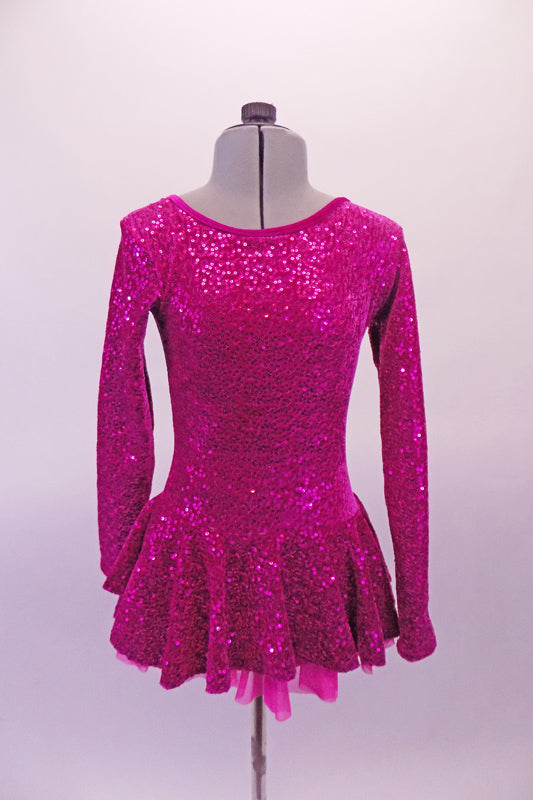 Velvet based long sleeved round neck skating dress is a beautiful fuchsia colour covered entirely in sequins. The attached flounce skirt has a layer of tricot for a bit of volume. The back is unique with triple cross-over straps that extend from the shoulders in an angle across the back. Front