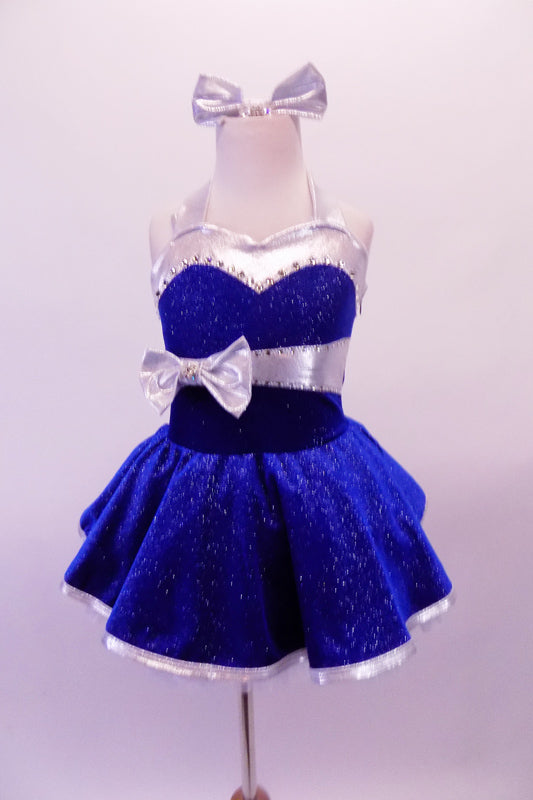 Royal blue glitter velvet halter dress has shimmery white satin trims. The sweetheart neckline is lined with crystals, as is the wider band below the bustline complete with large white bow accent. The attached white petticoat gives the skirt the poufy volume. Comes with short white satin gloves and matching hair bow. Front
