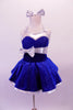 Royal blue glitter velvet halter dress has shimmery white satin trims. The sweetheart neckline is lined with crystals, as is the wider band below the bustline complete with large white bow accent. The attached white petticoat gives the skirt the poufy volume. Comes with short white satin gloves and matching hair bow. Front