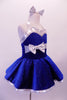 Royal blue glitter velvet halter dress has shimmery white satin trims. The sweetheart neckline is lined with crystals, as is the wider band below the bustline complete with large white bow accent. The attached white petticoat gives the skirt the poufy volume. Comes with short white satin gloves and matching hair bow. Side