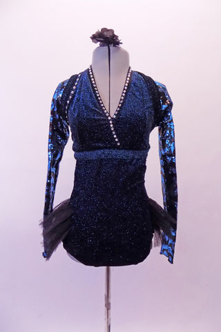 Black and teal glittery leotard dress has crossover front halter neckline and open back edged with crystals. The attached open-front, black tutu bustle skirt gives a bit of flare.  The teal and black, sequined shrug completes the look. Comes with a black floral hair accessory. Front