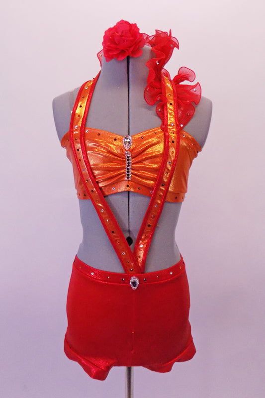 Orange bandeau & and a red brief costume is connected by a band that originates at the front of the waist in a V-shape that connects at the back of the neck. A red ruffle runs along the band of the left bust to the neck. The bandeau, waist & bands are covered with crystals. Comes with a floral hair accessory. Front