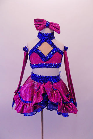 Two-piece costume is a magenta skirt with royal blue sequined ruffle trim and waistband and layered royal bluer ruffled petticoat. The matching top is a halter cut with a faux sweetheart cut with royal blue sequin banding that extends along the back. Comes with long gauntlets and a magenta bow hair accessory. Front
