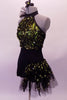 Short unitard is a halter style with a black short bottom. The top is a lime green with black sequined lace overlay. Two vertical straps extend from the back of the neck to support the back. There is a ruffled tulle accent at the left side of the neck that matches the ruffle accent at the left hip. Left side